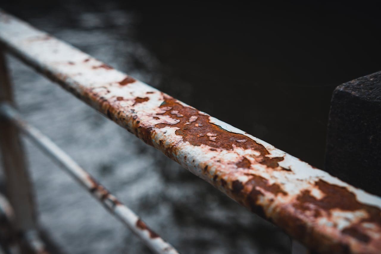 Corroded metal railing near water surface showing typical coastal steel degradation