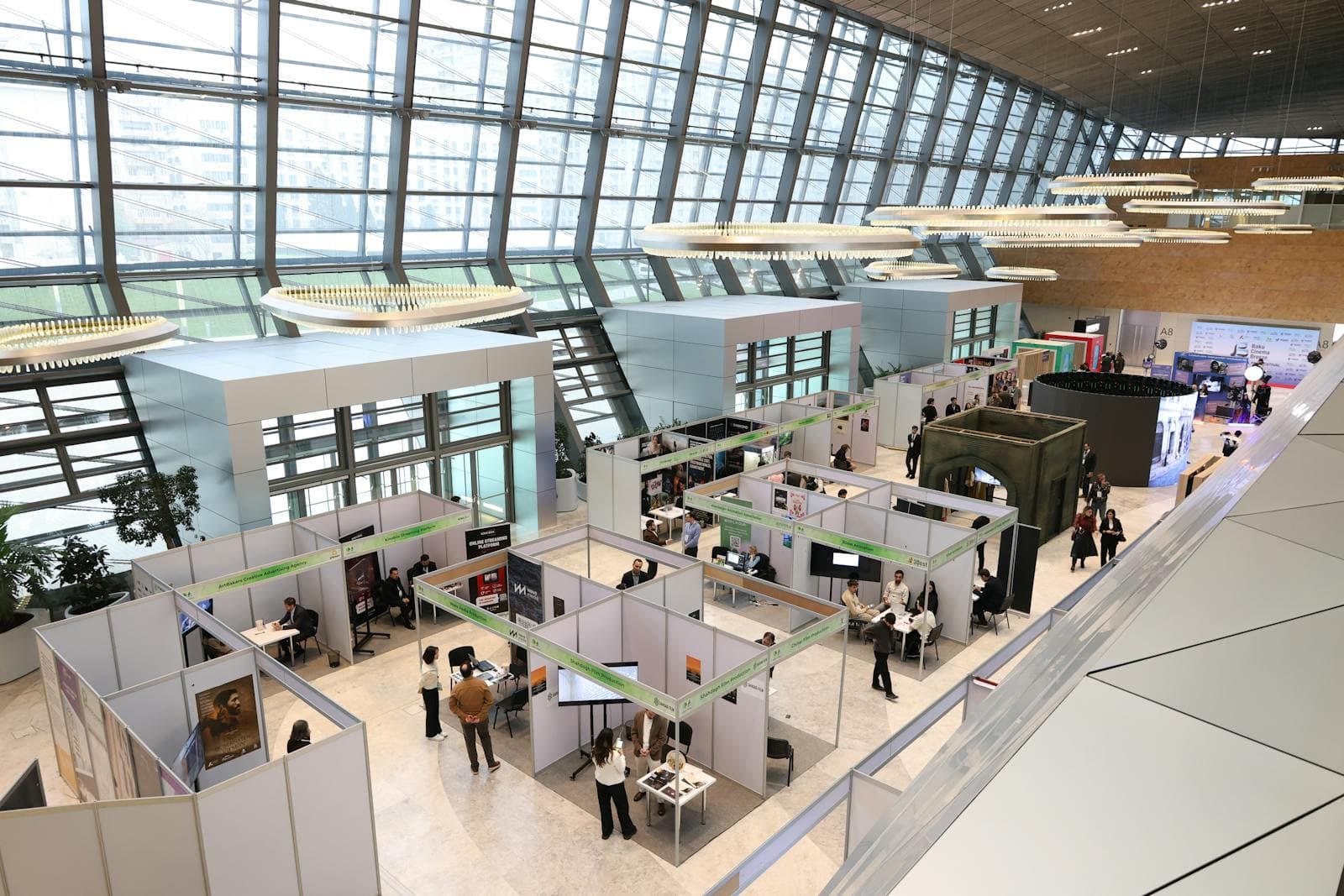 Modern trade-show exhibition hall with attendees networking across multiple booths